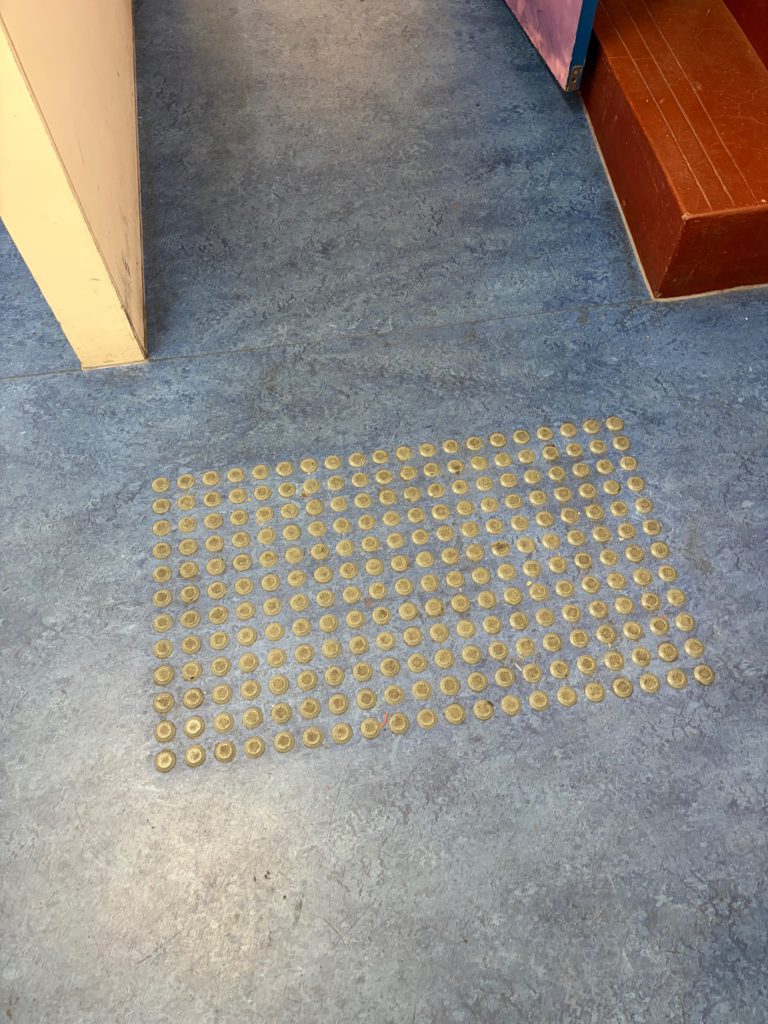 Tactile indicators on the blue floor surface near the venue entrance.
